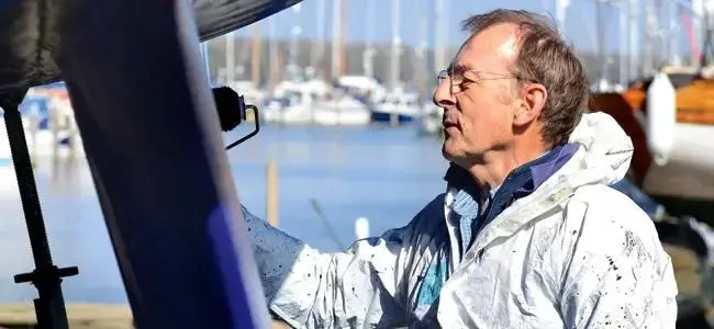 A boat owner roller applying primer to the keel of his vessel